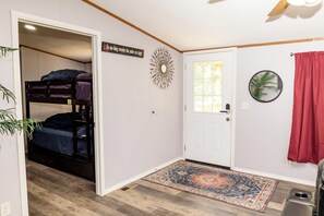 A room with a bunk bed, a decorative wall piece, a door with a window, and a patterned rug. - Hidden Creek Guest Wing, Private 3BR Retreat Sleeps 10 (Huntsville)