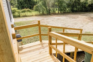 Eine Holzterrasse mit Blick auf eine Rasenfläche und Bäume.