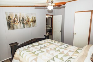 Ein Schlafzimmer mit Bett, Deckenventilator, Stadtbildgemälde und einer Tür zu einem Kleiderschrank.