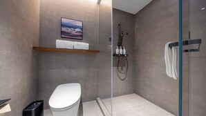 Ein modernes Badezimmer mit Toilette, einer Duschkabine aus Glas und einem Ablagefach für Toilettenartikel.