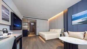 Ein modernes Hotelzimmer mit einem Bett, einer Sitzecke, einem Flachbildfernseher und einem Bild an der Wand.