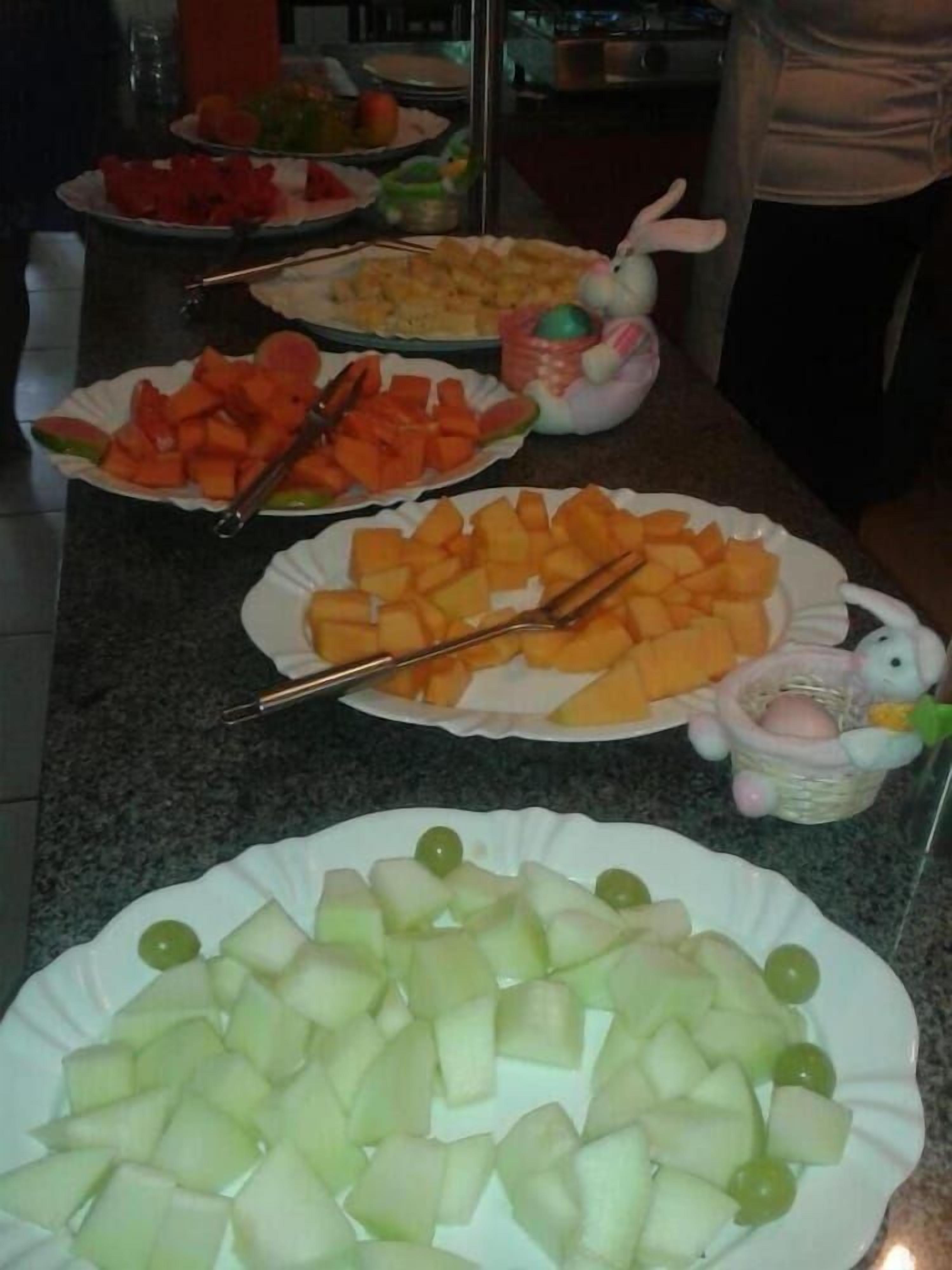 A table with various fruit platters, including melon and grapes.