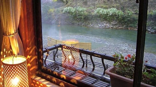 Vista desde una ventana con barandilla metálica, una mesa y una planta en maceta.