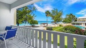 Ein Balkon mit Blick auf einen Strand, ein Schwimmbad und ein Gebäude.