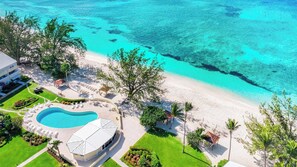 An aerial view of a resort with a swimming pool, beach, and clear turquoise waters. - Harbour Heights #19 Seven Mile Beach, 2 Bed, 2 Bath Ground Floor Condo (Seven Mile Beach)