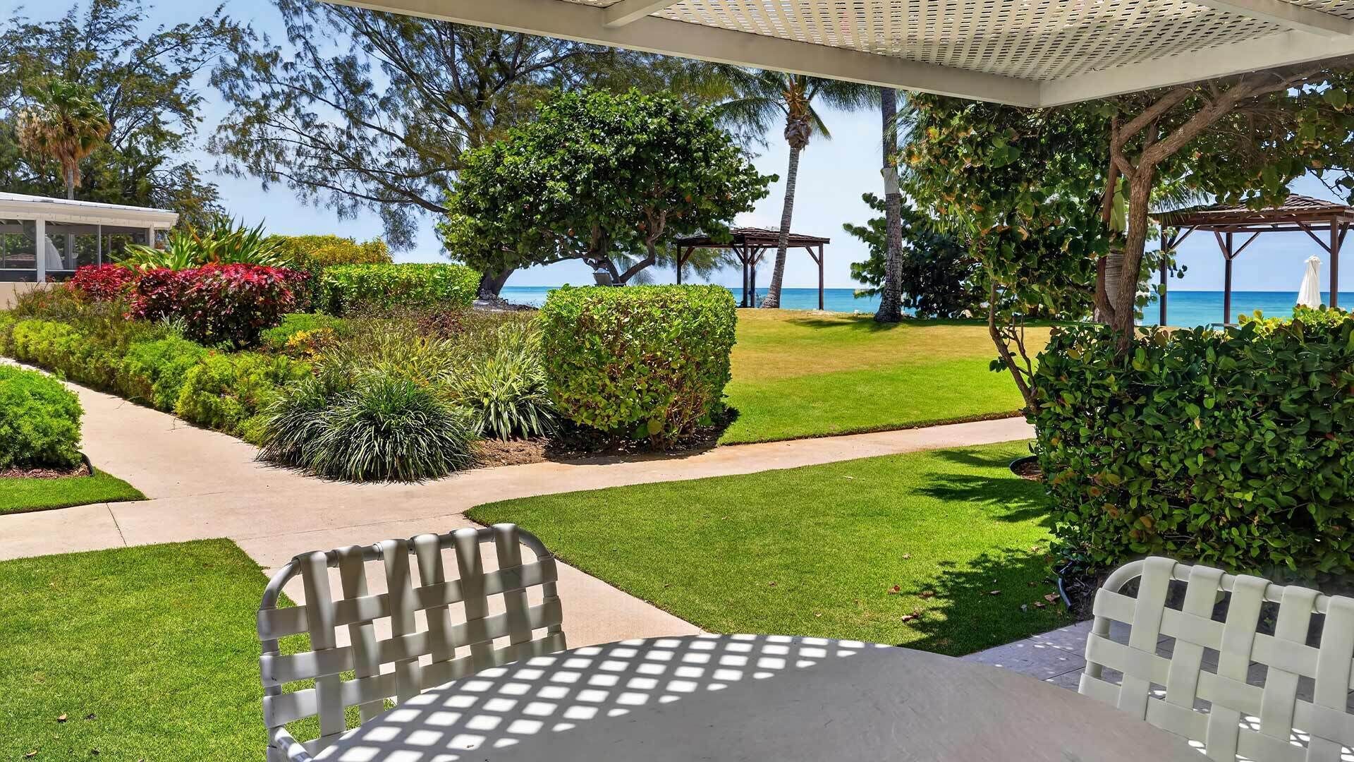 A patio area with a table and chairs, surrounded by well-maintained landscaping and a view of the ocean.