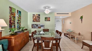 A dining area with a glass table, wooden chairs, and a white ceiling fan. - Harbour Heights #19 Seven Mile Beach, 2 Bed, 2 Bath Ground Floor Condo (Seven Mile Beach)