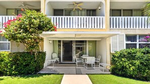 Un bâtiment à deux étages doté d’un balcon, d’un patio couvert aménagé avec du mobilier d’extérieur et d’un jardin bien entretenu.