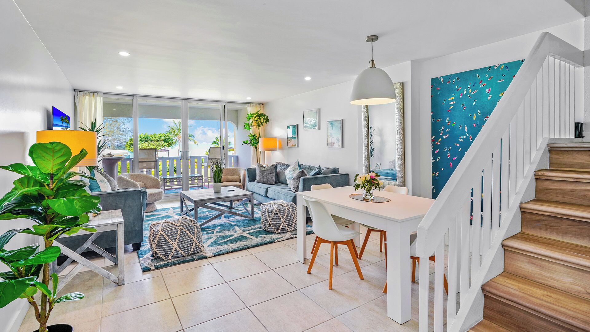 A modern living room with a dining area, a staircase, and a view of the outdoors.