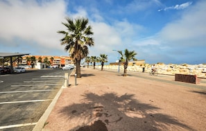 A parking area with marked spaces, a covered shelter, and a row of palm trees. - 5 bedroom cozy home in Sainte Marie La Mer Pl (Sainte Marie La Mer Pl)