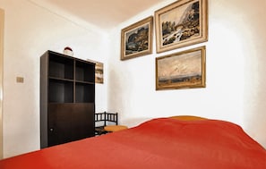Ein Zimmer mit einem Bett, einem Kleiderschrank und drei gerahmten Bildern an der Wand.