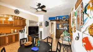 A kitchen with wooden cabinets, a dining table with chairs, a ceiling fan, and a wall with various decorations. - 5 bedroom cozy home in Sainte Marie La Mer Pl (Sainte Marie La Mer Pl)
