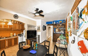 A kitchen with wooden cabinets, a dining table with chairs, a ceiling fan, and a wall with various decorations. - 5 bedroom cozy home in Sainte Marie La Mer Pl (Sainte Marie La Mer Pl)