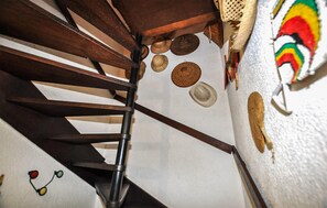Ein Holzstuhl mit Metallgestell, eine weiße Wand mit strukturierter Oberfläche und ein farbenfrohes, abstraktes Gemälde.