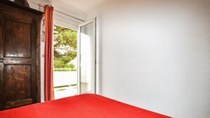 A room with a wooden wardrobe, a red bedspread, and a white wall. - 5 bedroom cozy home in Sainte Marie La Mer Pl (Sainte Marie La Mer Pl)
