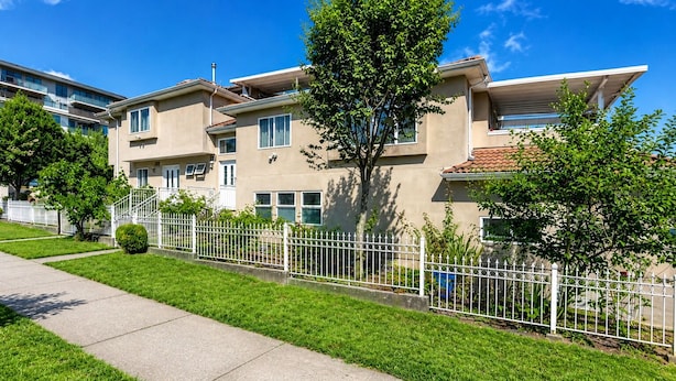 A residential building with multiple floors, a white fence, and a well-maintained lawn. - Cozy Home in Vancouver (Vancouver)