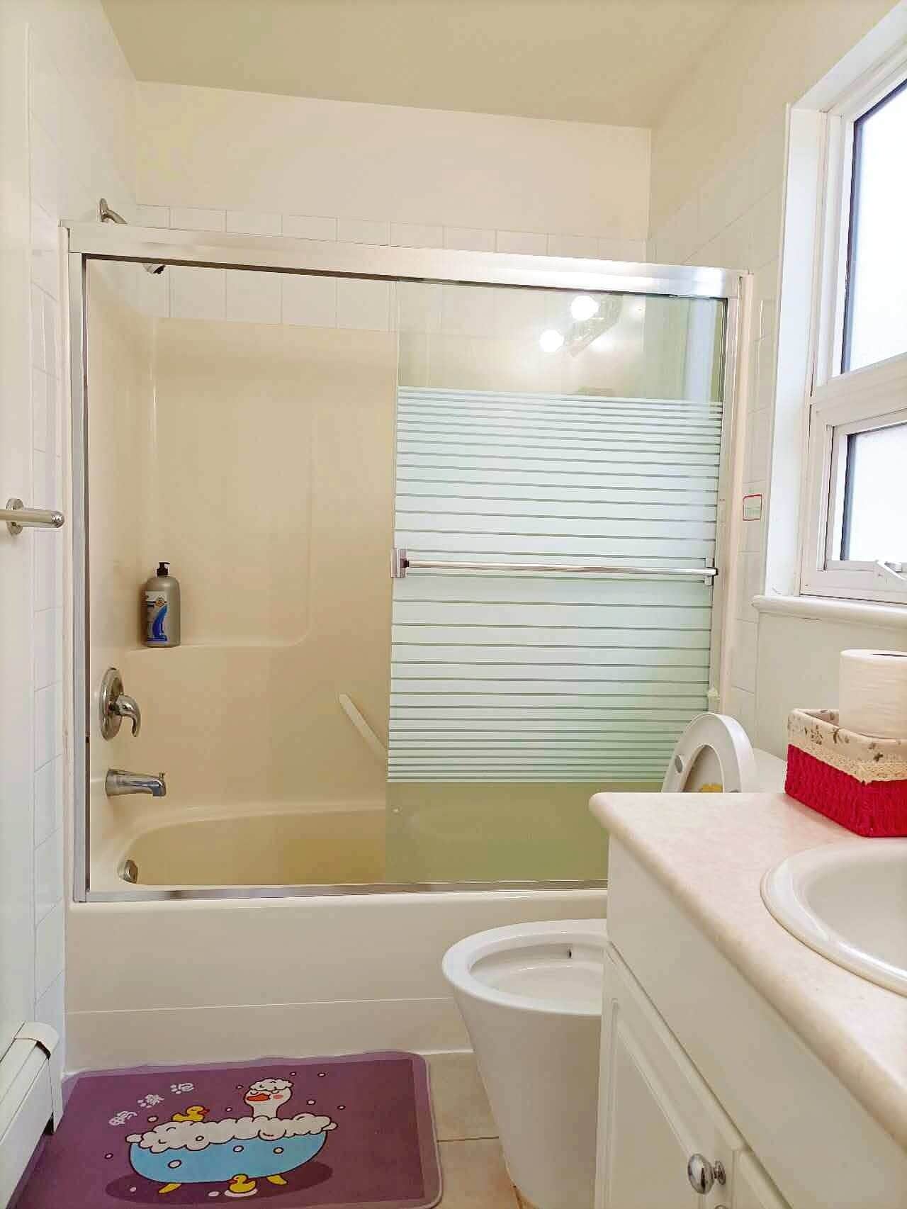 A bathroom with a glass-enclosed shower, a toilet, and a sink.