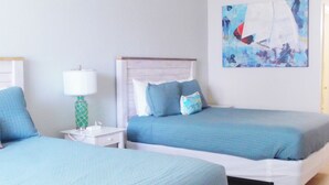 A hotel room with two beds, a nightstand, a lamp, and a wall painting. - Direct Oceanfront Daytona Beach Condo | Full Kitchen | Beach Access (Daytona Beach)