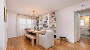 A dining area with a wooden table, chairs, and a bookshelf filled with various items.