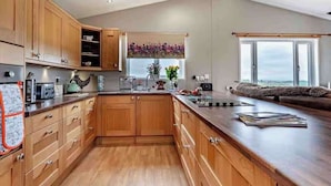 A modern kitchen with wooden cabinets, a large island, and a view of the outdoors.