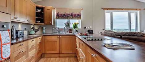A modern kitchen with wooden cabinets, a large island, and a view of the outdoors.