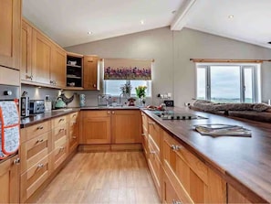 A modern kitchen with wooden cabinets, a large island, and a view of the outdoors.