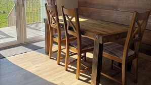 A dining area with a wooden table and chairs, a sliding glass door leading to a balcony, and a framed picture on the wall.