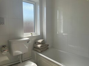 Ein Badezimmer mit Toilette, Waschbecken, Fenster und Badewanne.