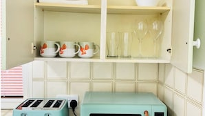 A kitchen with a toaster, a microwave, and a cabinet containing mugs and glasses. - Cozy Grays Apartment (Grays)