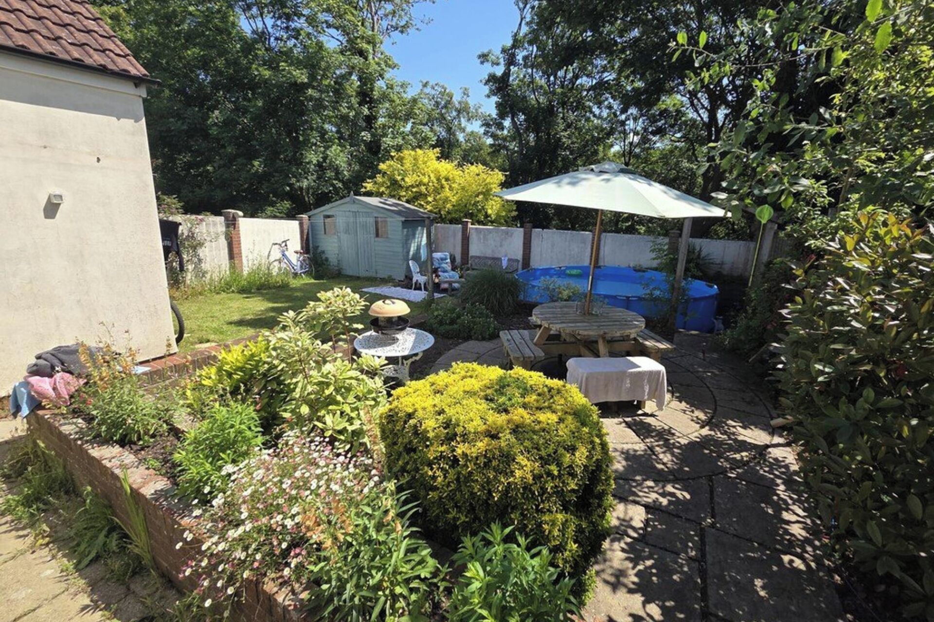 A backyard with a pool, outdoor furniture, and a shed.