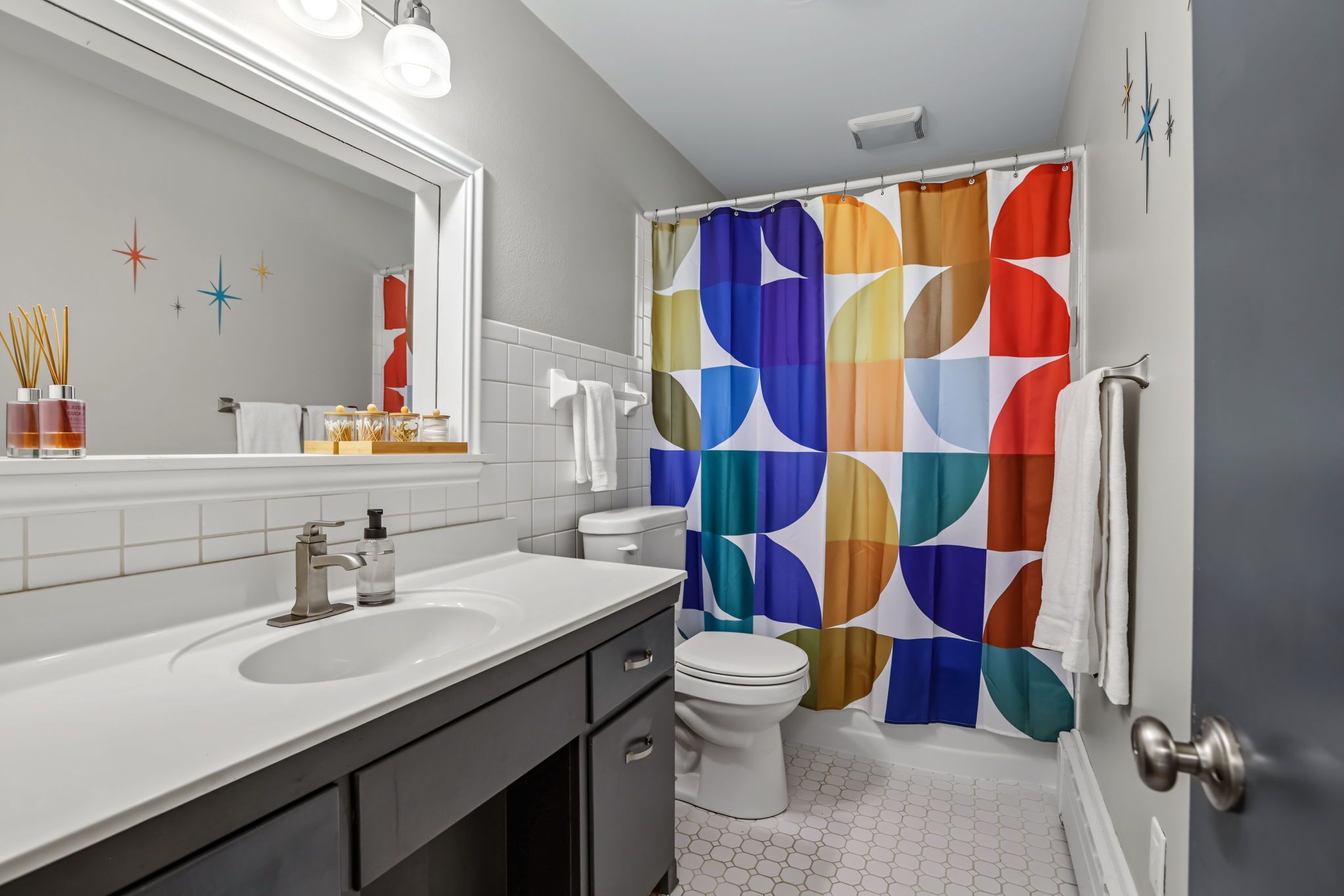 A modern bathroom with a white sink, a toilet, and a colorful shower curtain.