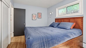 Una camera da letto con un letto, una testata in legno, una finestra con vista e una porta che dà su un'altra stanza.