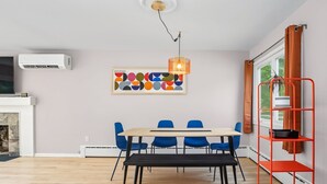 Un soggiorno moderno con un tavolo da pranzo, sedie blu, una mensola metallica rossa e un'opera d'arte Bauhaus appesa al muro.