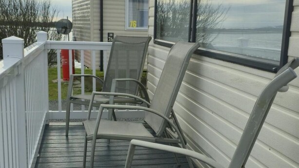 A covered outdoor area with metal chairs and a white railing.