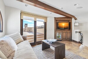 Ein modernes Wohnzimmer mit einer Couch, einem Couchtisch und einem an einem Holzkasten montierten Fernseher.