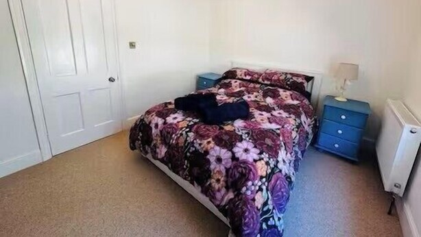 Een slaapkamer met een bed, een dressoir, een nachtkastje en een radiator.