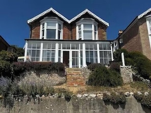 Ein zweistöckiges Haus mit Wintergarten, Ziegelmauern und einem Steinfundament.
