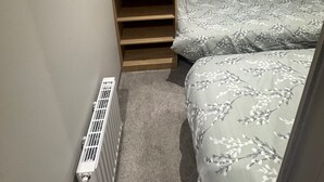A bedroom with a wooden wardrobe, a window with curtains, and a bed with a floral bedspread. - Sleeps6-BeachCaravan-FreeParking-Porthcawl (Porthcawl)