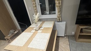 A room with a long wooden table, a radiator, a television, and a window with curtains. - Sleeps6-BeachCaravan-FreeParking-Porthcawl (Porthcawl)