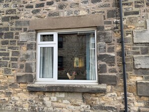 A stone building with a window featuring white trim and a small overhang.