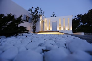 A modern building with a white facade, vertical windows, and a well-lit entrance. - Aeolos Resort (Mykonos)