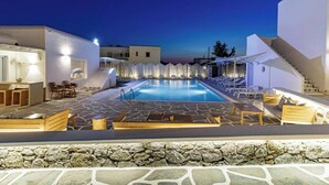 A pool area with lounge chairs and a stone-tiled deck. - Aeolos Resort (Mykonos)