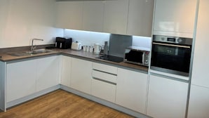 A modern kitchen with white cabinets, a stainless steel sink, a toaster, a coffee maker, and a microwave. - Southampton 2-Bed Apartment, Sleeps 4 with Balcony (Southampton)
