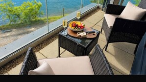 A balcony with wicker furniture, a glass table, and a bowl of fruit and cheese. - Southampton 2-Bed Apartment, Sleeps 4 with Balcony (Southampton)