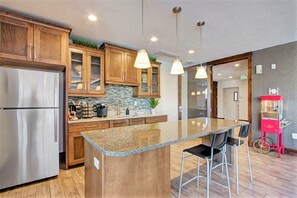 A modern kitchen with wooden cabinets, stainless steel appliances, and a granite island with bar stools. - Spacious 2-bedroom Executive Condo (Salt Lake City)