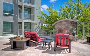 An outdoor patio with a stone fireplace, red cushioned chairs, and a table. - Spacious 2-bedroom Executive Condo (Salt Lake City)