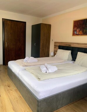 A hotel room with a large bed, a wardrobe, a painting on the wall, and a wooden floor. - Appartements Konrad (Soell)