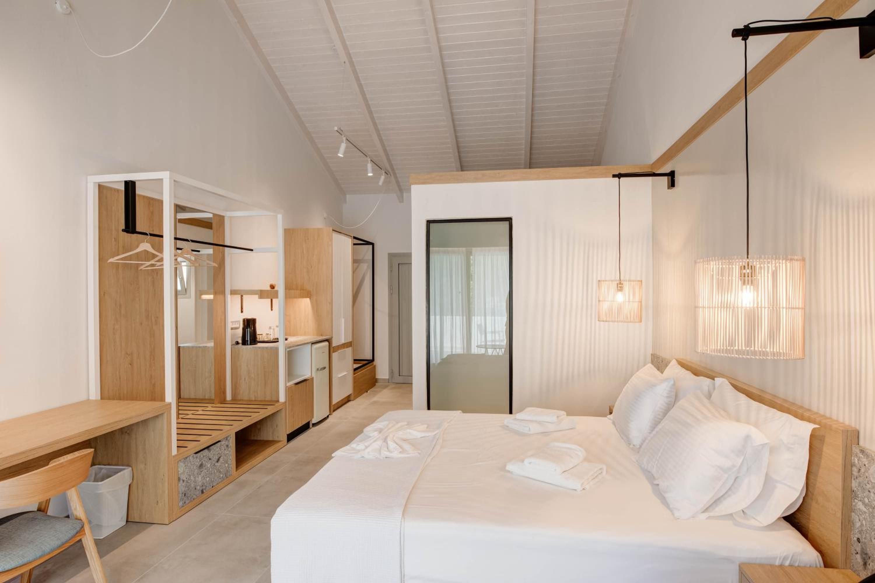 A modern hotel room with a bed, bedside tables, a wardrobe, and a desk.