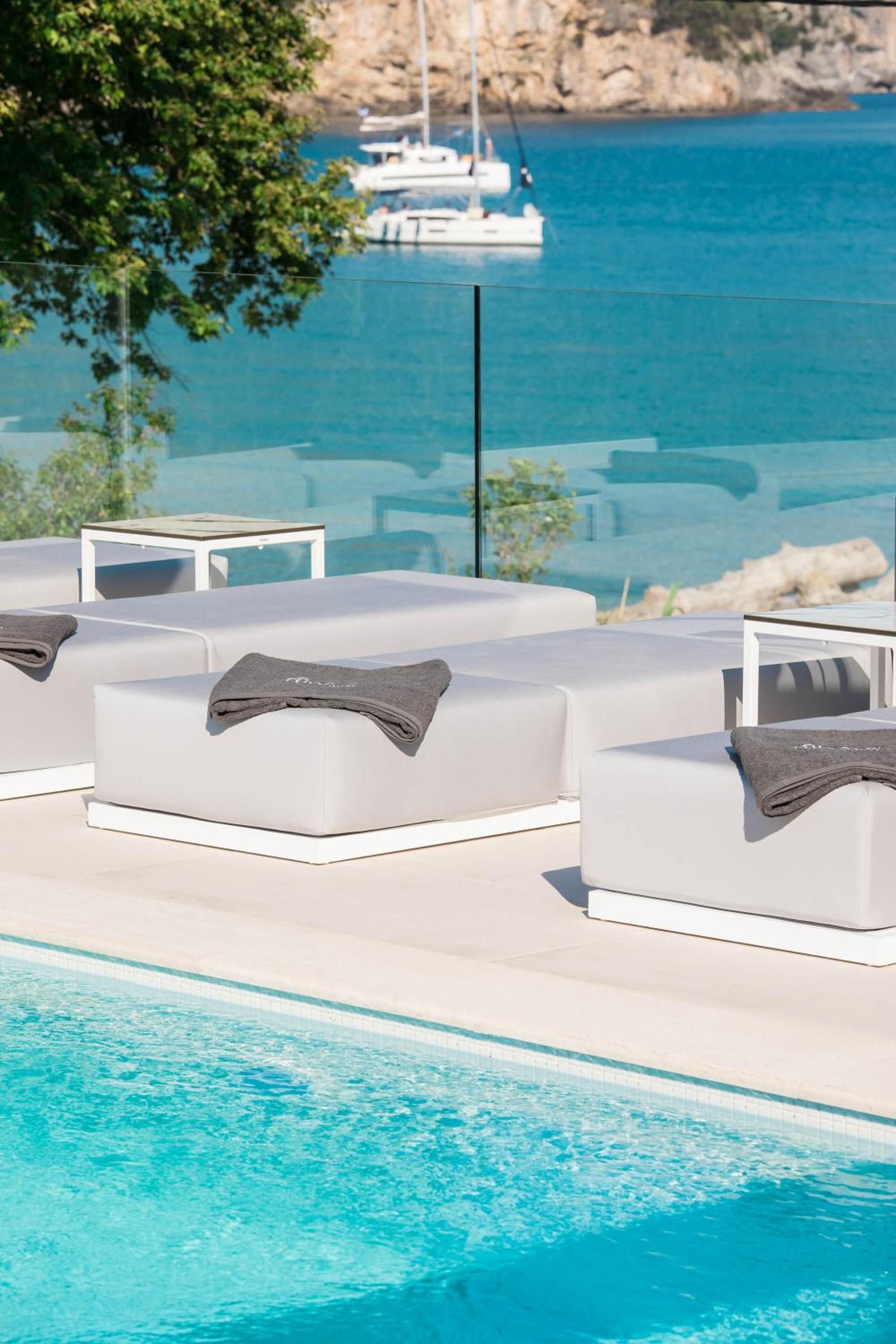 A poolside area with lounge chairs and a view of the sea.