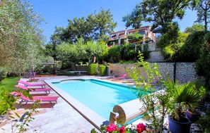 A swimming pool with lounge chairs and a stone wall. - Stunning home in Robion (Robion)